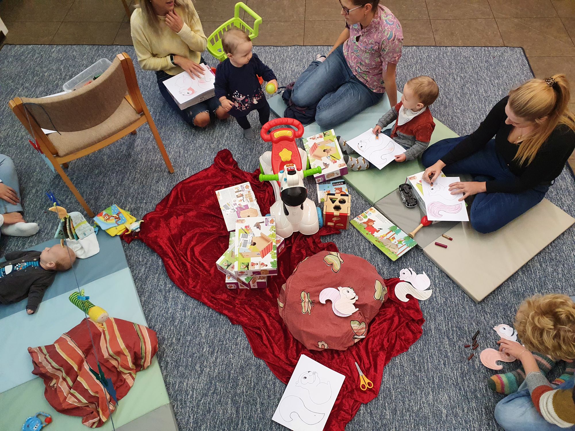 Eltern und Kleinkinder beim Malen und Spielen in einer Gemeindegruppe.