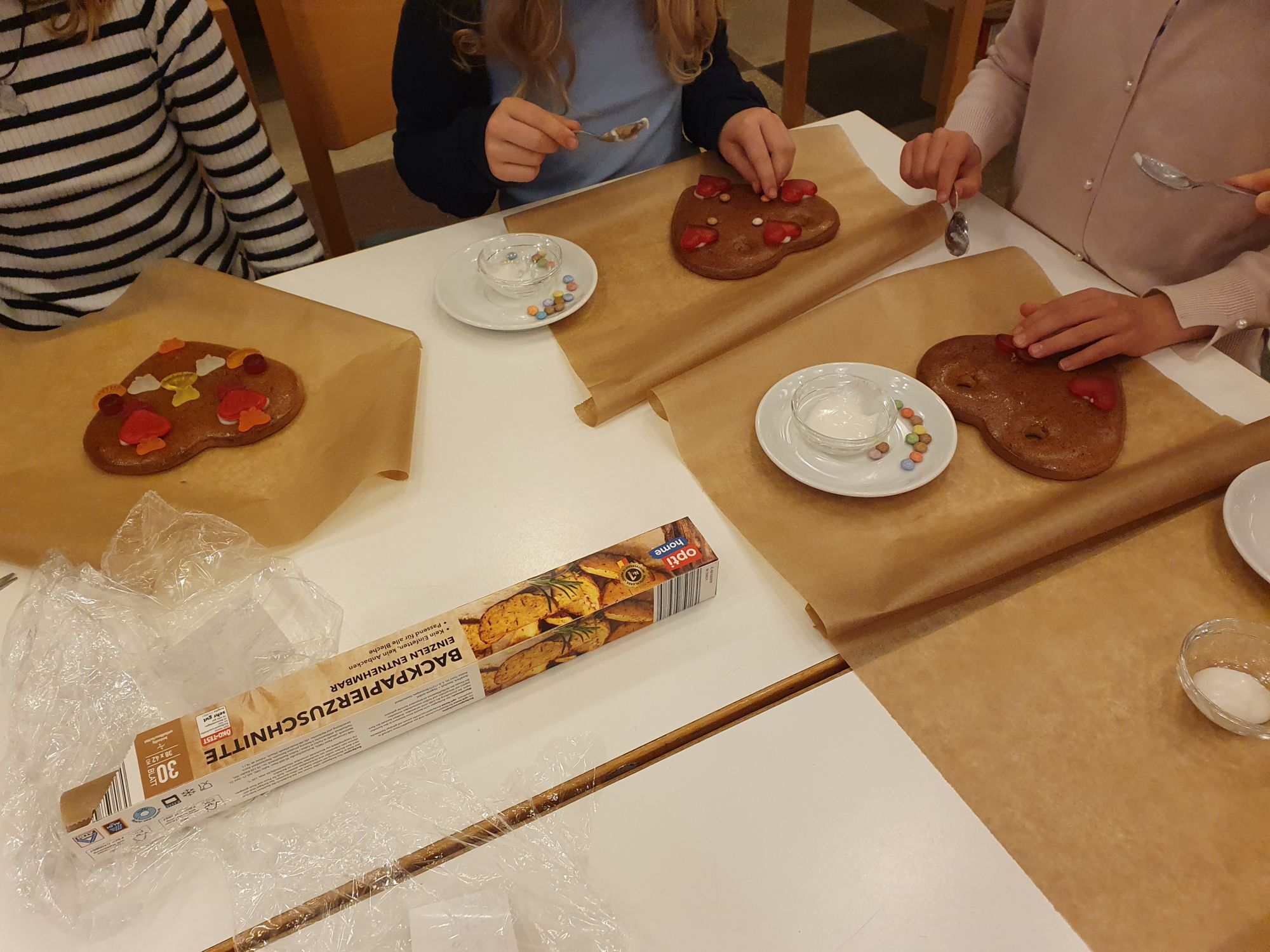 Kinder verzieren Lebkuchenherzen mit Süßigkeiten in einer Gemeindegruppe.